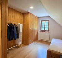 Ein Zimmer mit Holzvertäfelung und einem Boden in Holzoptik, einem Bett und einem Fenster.