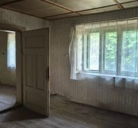 Ein altes Interieur in einem Einfamilienhaus mit Holzboden und Vorhängen an den Fenstern.