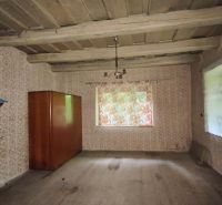 Alte Tapeten, Holzdecke, Regal und Schrank im Zimmer eines Einfamilienhauses.