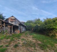 Ein älteres Familienhaus in Čelovce, umgeben von Grün, Rasen und blauem Himmel.