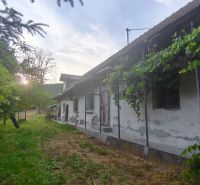 Ein älteres Familienhaus in Čelovce, umgeben von Grün mit einem Sonnenuntergang im Hintergrund.