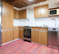 Küche in einem Einfamilienhaus mit Holzschränken und Kühlschrank.