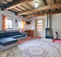 Wohnzimmer in einem Einfamilienhaus mit Holzbalkendecke, Sofa und Kachelofen.