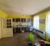 Küche in einem Einfamilienhaus mit gelben Wänden, braunem Teppich und Küchenzeile in Dolné Otrokovce.