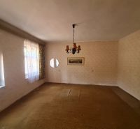 Innenraum eines Einfamilienhauses mit Teppichboden, Licht und Vorhängen an den Fenstern.