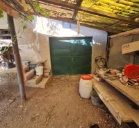 Garage bei einem Einfamilienhaus in Dolné Otrokovce mit einem Blechtor und einem Unterstand.