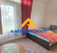 Ein Zimmer mit einem Bett, einem Fenster mit roten Vorhängen und einem Fernseher in einem Einfamilienhaus.