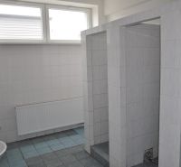Badezimmer in Produktionsräumen mit gefliestem Boden und mehreren Waschbecken.