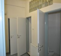 Offene Toilettentür in Produktionsräumen mit Fliesenboden und Waschbecken.