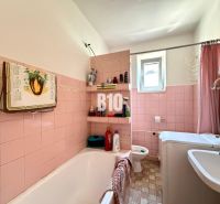 Ein Badezimmer in einem Einfamilienhaus mit rosa Fliesen und einer Badewanne.