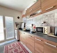 Küche in einem Einfamilienhaus mit Küchenzeile und Geräten, Boden mit Holzdekor.