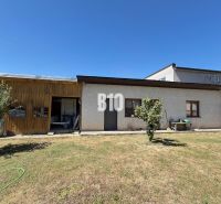 Ein Einfamilienhaus in Kláštor pod Znievom mit einem Holzvorbau und einem Rasen auf einem sonnigen Grundstück.