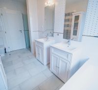 Ein Badezimmer mit zwei Waschbecken, einer Badewanne und Fliesen in einem Einfamilienhaus.