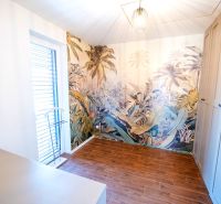Ein Zimmer in einem Einfamilienhaus mit exotischer Tapete und Boden in Holzoptik.