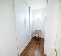 Ein enger Flur in einem Einfamilienhaus mit einem Holzboden und einem Fenster.