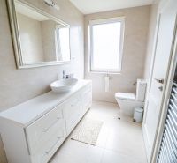 Ein Badezimmer in einem Einfamilienhaus mit einem weißen Waschbecken und einem großen Spiegel.