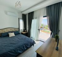 Schlafzimmer in einem Einfamilienhaus mit großem Bett und Boden in Holzoptik.