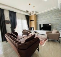 Wohnzimmer in einem Einfamilienhaus mit luxuriösem Sofa, Teppich und großem Fernseher.