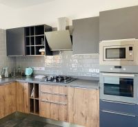 Eine Küche mit einem Holzboden und grauen Schränken in einem Einfamilienhaus.