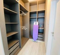 Ein Kleiderschrank im Einfamilienhaus mit Regalen, Kleiderbügeln und einem Bügelbrett.
