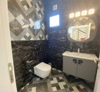Ein Badezimmer in einem Einfamilienhaus mit dunkler Verkleidung und geometrischen Mustern an den Wänden.