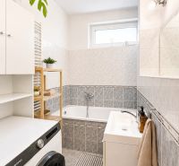 Badezimmer mit Dusche, Badewanne und Waschmaschine in einer 4-Zimmer-Wohnung.