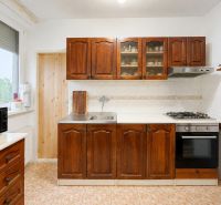 Küche mit Holzschränken und Fliesenboden in einer Vierzimmerwohnung.