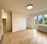 Wohnzimmer mit Holzboden in einer 3-Zimmer-Wohnung und Küchenzeile.