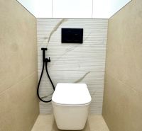 Ein Badezimmer mit einer weißen modernen Schüssel, einer Duschgarnitur und Fliesen mit dekorativem Muster.