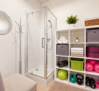 Duschkabine, Regale mit Handtüchern und Fitnessgeräten in Geschäftsräumen.