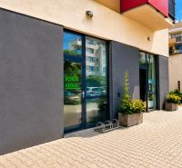 Geschäftsräume in der Okružná-Straße in Stupava mit moderner Fassade und Blumen vor dem Eingang.