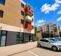 Geschäftsräume in der Okružná-Straße in Stupava, Parkplatz mit Autos, Balkone und Café.