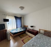 Schlafzimmer in einem Einfamilienhaus mit Betten, Fernseher und einem Boden mit Holzdekor.