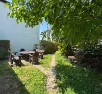 Der Garten des Einfamilienhauses in der Senna-Straße in Bratislava - Ružinov, mit einer Sitzgelegenheit im angenehmen Schatten.