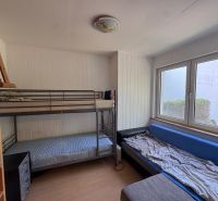 Ein Zimmer mit einem Etagenbett, einem ausziehbaren Sofa und einem Regal in einem Einfamilienhaus.