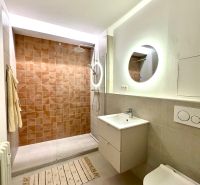 Badezimmer in einer Einzimmerwohnung mit begehbarer Dusche und rundem Spiegel.