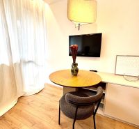 Ein Tisch mit einem Stuhl und einem Fernseher in einer Einzimmerwohnung, Boden mit Holzdekor.