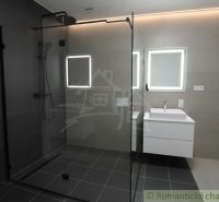 Badezimmer in einem Einfamilienhaus mit verglaster Duschkabine und beleuchteten Spiegeln.