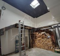 Ein Einfamilienhaus mit Holzbalken und gelagertem Holz im Innenraum.