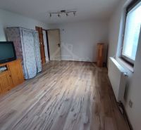 Ein Zimmer in einem Einfamilienhaus mit einem Fernseher und einem Boden in Holzoptik.