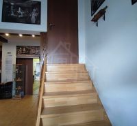 Eine Treppe mit einem Boden in Holzoptik und Kunstbildern an den Wänden in einem Einfamilienhaus.