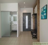 Ein Flur mit Keramikfliesen, Glastüren, einem Waschbecken und einer Garderobenwand in einem Einfamilienhaus.