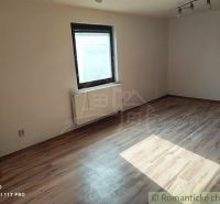 Ein Zimmer mit einem Holzboden und einfacher Einrichtung in einem Einfamilienhaus.