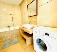 Badezimmer mit Badewanne und Waschmaschine in einer 4-Zimmer-Wohnung, Boden mit Holzdekor.