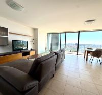Helles Wohnzimmer mit Sofa, Fernseher und großen Fenstern, 4-Zimmer-Wohnung.