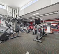 Fitnesszentrum mit Kraftgeräten, Spiegeln und Lüftungstechnik in Geschäftsräumen.