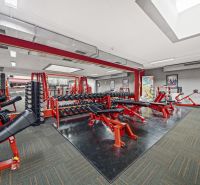 Fitnesscenter mit Kraftgeräten, Bänken und Spiegeln in Geschäftsräumen.