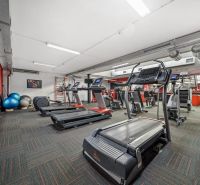 Fitnesszentrum mit Laufbändern und Trainingsgeräten in Geschäftsräumen.
