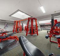Fitnesscenter mit Kraftgeräten und roten Bänken, geeignete Geschäftsräume.