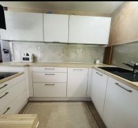Küche in einer 3-Zimmer-Wohnung mit weißen Schränken und einer Arbeitsplatte in Holzoptik.